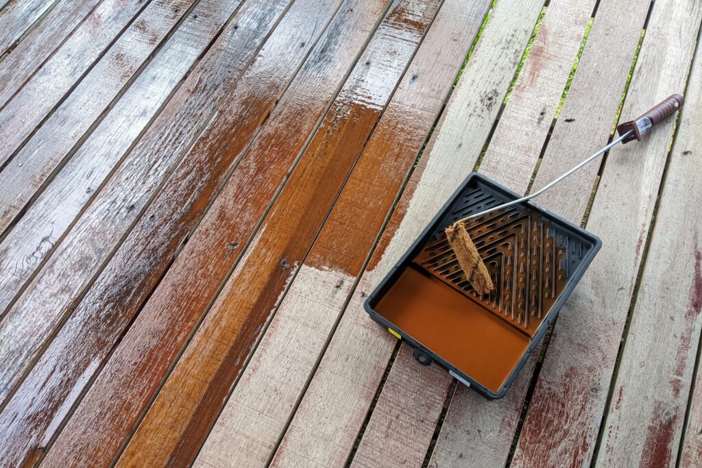 Deck staining tools beside wooden floor