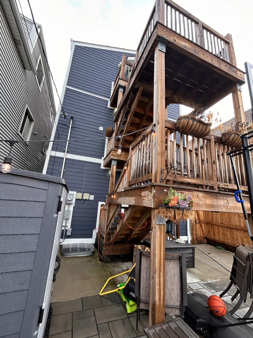 Three-story wood back porch on a Chicago multi-unit building, gray and weathered before restoration