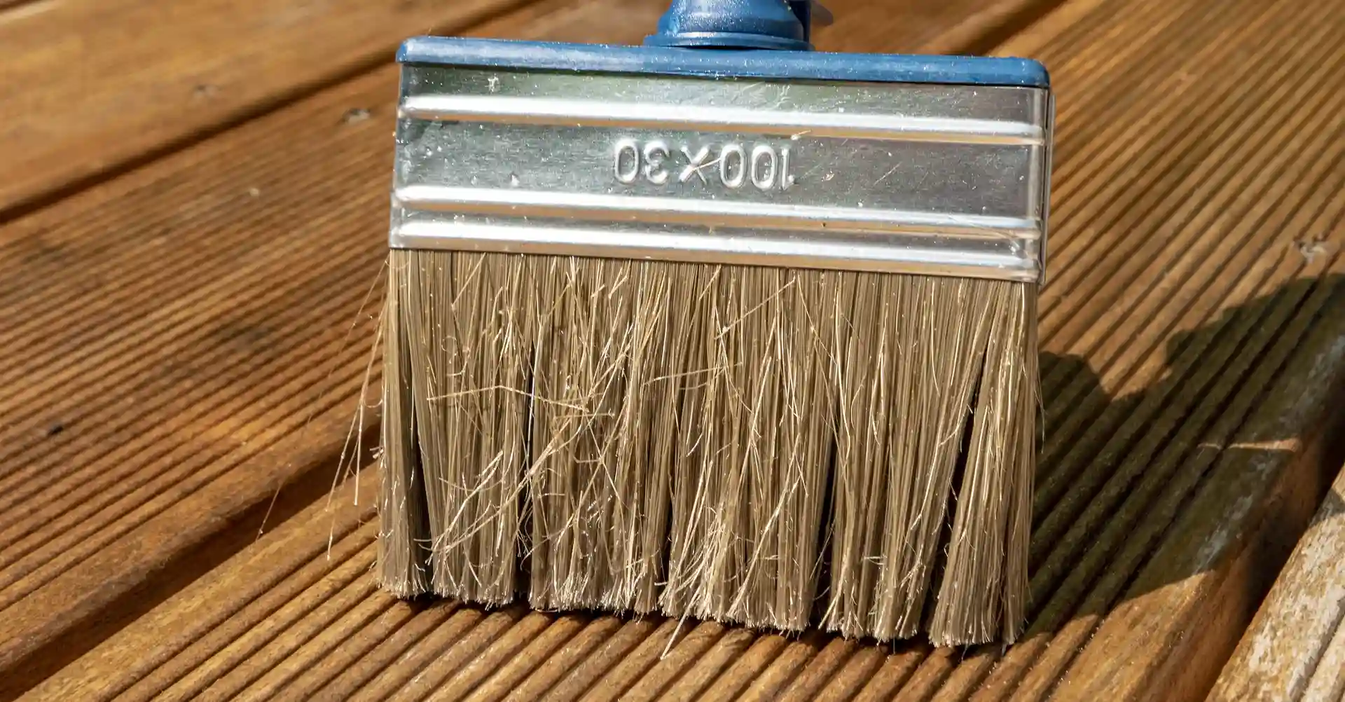 Brush applying fresh stain and sealer to a clean wood deck during professional deck services in Chicago